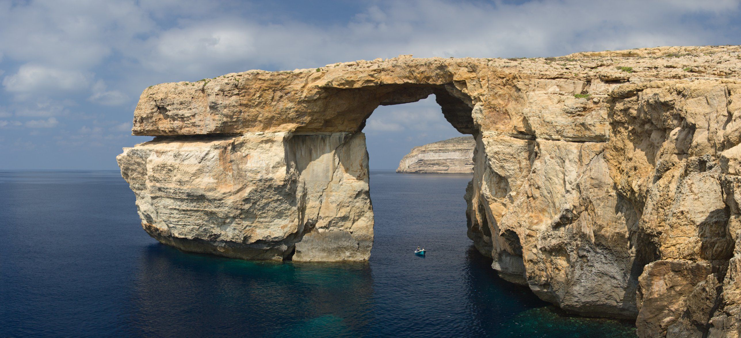 The Azure Window at Dwejra photographed before it collapsed into the sea in March 2017, a limestone arch with a small boat passing beneath it