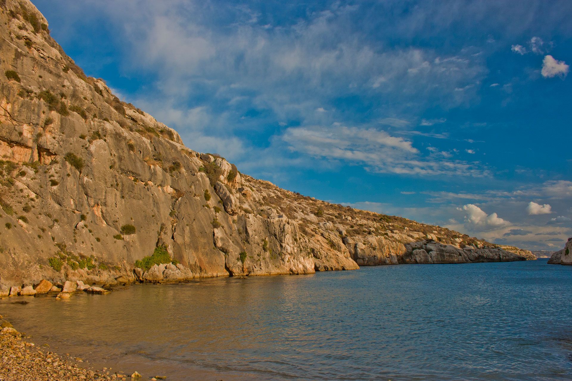 The cliffs and pebble shore at the head of Mġarr ix-Xini, the narrow inlet on Gozo’s south coast, in late afternoon light