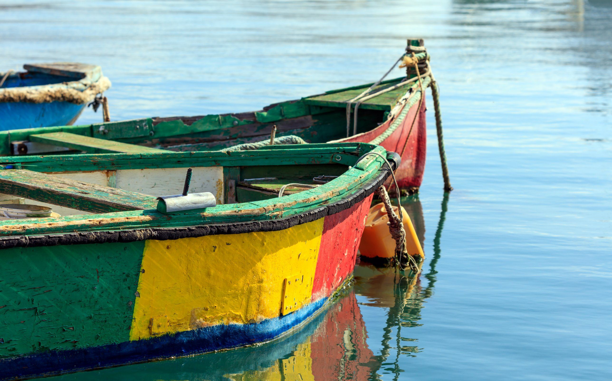 Traditional Maltese fishing boats painted green, red, yellow and blue, moored on still water